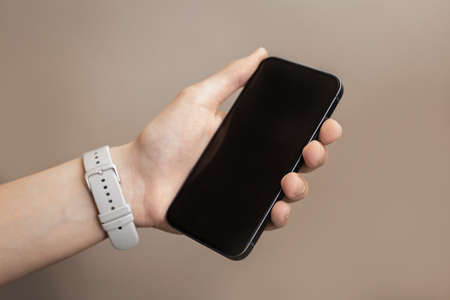 Smartphone in hand. A hand with a clock is holding a smartphone.