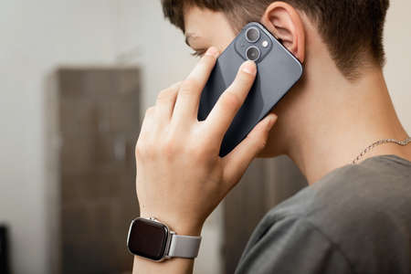 The guy is talking on the phone. Close-up of a phone. Smartwatch on the wrist. Smartphone with two...