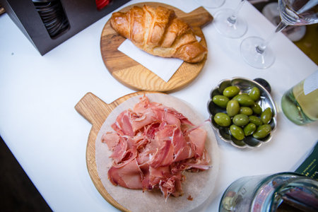 Sliced jamon on a wooden board, pastry croissant and green olivesの写真素材