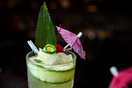 Summer alcoholic cocktail with mint and cucumber and pineapple and with umbrellaの写真素材