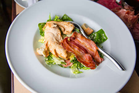 Salad with meat in a bowl. The waiter is holding a plate of salad close-up.の写真素材