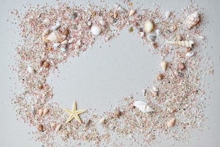 Cockleshells and pink sand with a starfish on a paper background with empty space for text.の写真素材