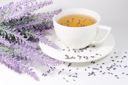 White porcelain cup with natural lavender tea near its flowers branchの写真素材