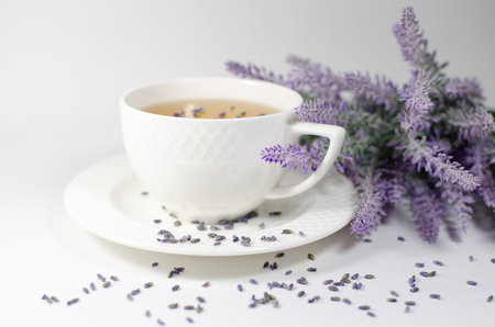 White porcelain cup with natural lavender tea near its flowers branchの写真素材