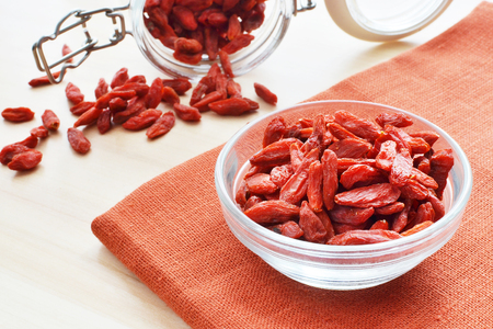 red goji berry in a glass bowl over terracotta flax background healthy food conceptの写真素材