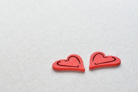 two red wooden hearts on grey paper background love conceptの写真素材
