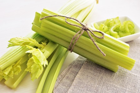 bunch of stalks of fresh green celery on flax material background, tied up by flax rope, healthy lifestyle conceptの写真素材