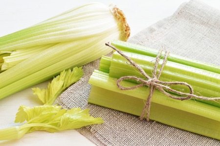bunch of stalks of fresh green celery on flax material background
