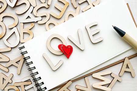 notebook with love wooden letters and pen, saint valintines day greeting card conceptの写真素材