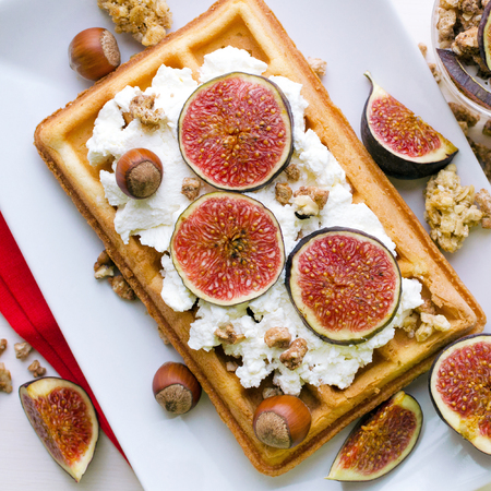 Vienna wafer dessert with ricotta, nuts and fresh figs on white plate over wooden background, square, top viewの写真素材