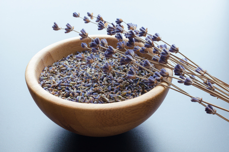 wooden bowl with dried lavender tea and flowers over blue backgroundの写真素材