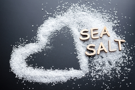 Sea Salt Crystals In heart shape over black chalk board background, healthy food conceptの写真素材