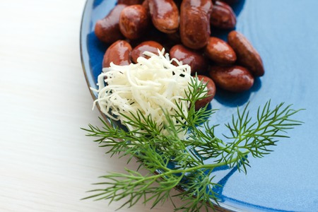 red canned beans with fresh dill and horseradish in blue ceramic plate over white backgroundの写真素材