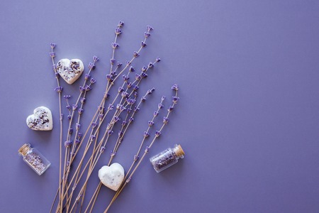 natural lavender dry flowers bunch with spa hearts and small bottles with buds over purple background, top view, copy spaceの写真素材