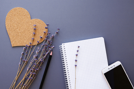 stylish working place flatlay with opened notebook, pencil, smartphone, cork heart and lavender dry flowers bunch, top viewの写真素材