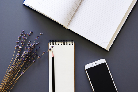 working space flatlay with opened diary and notepad, black pencil, smartphone mock up and lavender bunchの写真素材