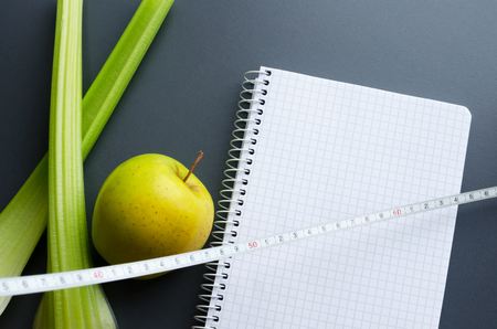 blank notebook, green apple, celery and measuring tape, copy space, diet plan, healthy food conceptの写真素材