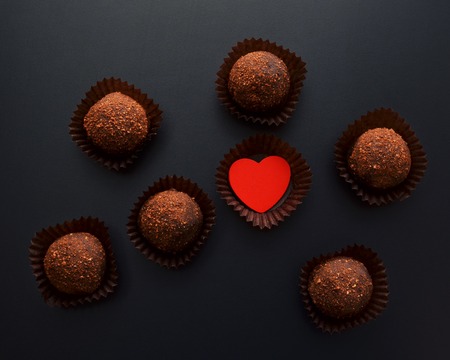 chocolate sweets in wrapper with red heart over black backgroundの写真素材