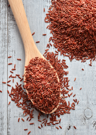 red rice on wooden spoon over wooden backgroundの写真素材