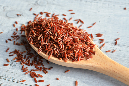 red rice on wooden spoon over wooden backgroundの写真素材