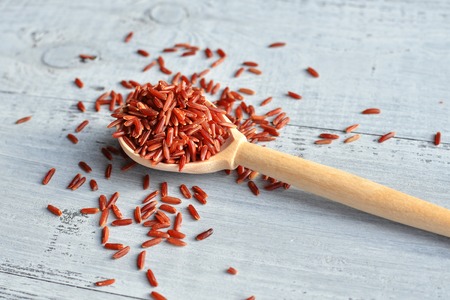 red rice on wooden spoon over wooden backgroundの写真素材