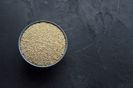 Dry organic quinoa seeds in gray ceramic bowl on dark grunge background, top view, healthy food conceptの写真素材
