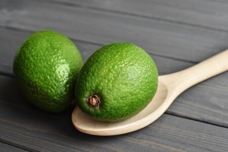 Whole organic fresh avocado fruit in wooden spoon on dark wooden vintage table background, side view - Imageの写真素材