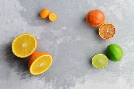 Citrus fruits layout frame. Orange, kumquat, lime and bloody orange composition on grey concrete background. Flat lay, top view, copy space.の写真素材