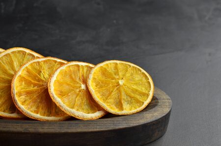 Organic vegan orange fruits chips in wooden plate on dark backgroundの写真素材