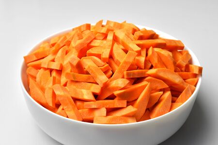 White bowl with chopped carrot. Mediterranean diet. Vegan food preparation concept.の写真素材