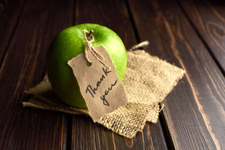 Apple with thank you lable on a piece of burlap over dark wooden background. Happy thanksgiving day...