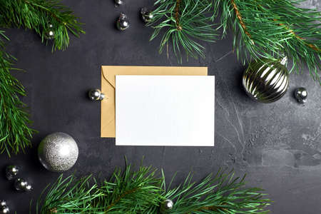 Greeting card mockup with pine tree branches and christmas decorations on dark background. Top view, copy space.の写真素材