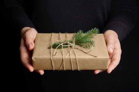 Female hands holding Christmas gift box over black backgroundの写真素材