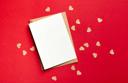 Valentines day card mockup with envelope and small paper hearts on red background, top view, copy spaceの写真素材