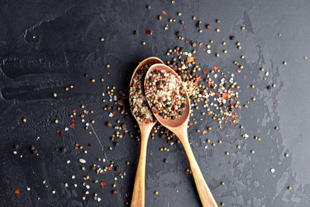 Different spices blend in wooden spoons on dark slate background. Pepper mix, sea salt, cardamon, mustard seeds and paprika flakes. Top view. Copy space. Food ingredients photographyの写真素材