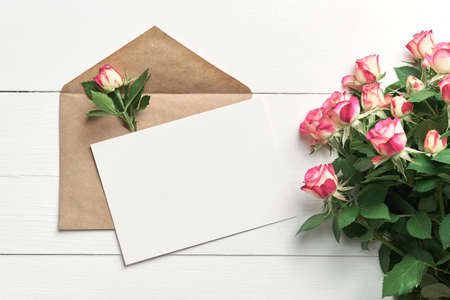 Greeting card mockup with fresh roses on white wooden backgroundの写真素材