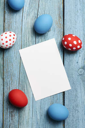 Easter holiday greeting card mockup with copy space, old blue wooden background, colored eggs.