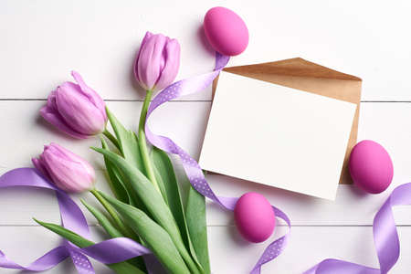 Easter holiday card with copy space, colored eggs, ribbons and spring tulips on pinkの写真素材