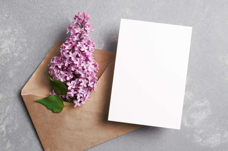 Greeting or invitation card mockup with envelope with lilac flowers on grey background, top view, copy spaceの写真素材