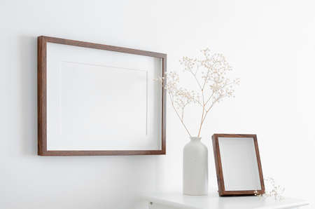 Blank landscape and portrait frames mockup on white wall with dry gypsophila plant decorations....