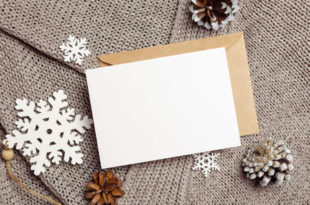 Christmas or New Year greeting card mockup with envelope, cones and wooden snowflakes decorationsの写真素材