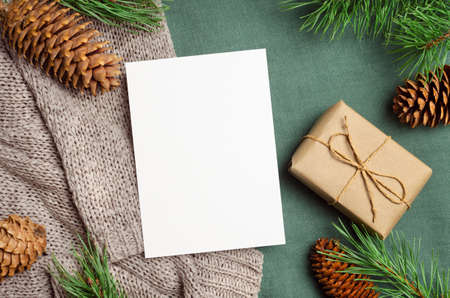 Christmas or New Year greeting card mockup with gift box and fir tree branches with conesの写真素材