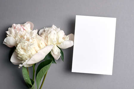 Greeting card mockup with copy space and white peony flowers on greyの写真素材