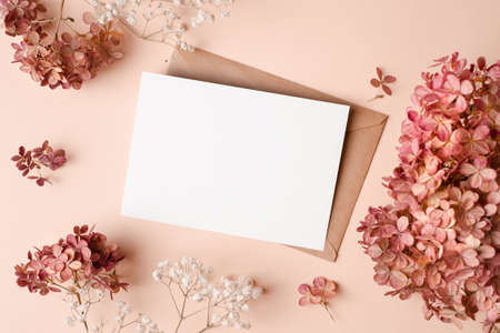 Invitation card mockup with envelope, dry hydrangea and gypsophila flowers decorations. Blank...
