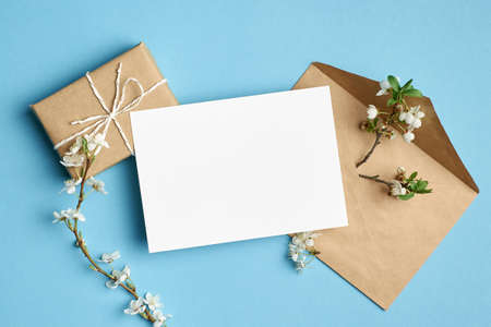 Greeting card mockup with gift, envelope and white flowers on blue backgroundの写真素材