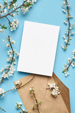 Greeting card mockup with envelope and white cherry flowers on blue backgroundの写真素材