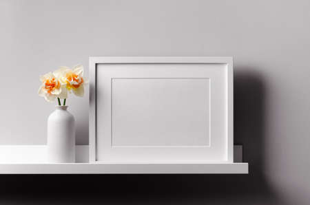 Landscape frame mockup on shelf with daffodils flowers, minimalistic interior mockup