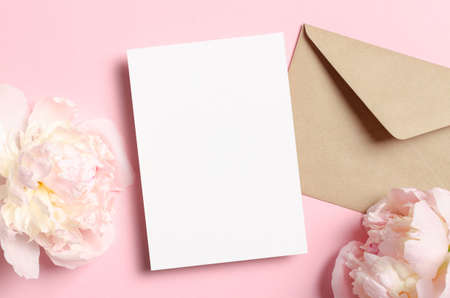 Blank greeting or invitation card mockup with envelope and pink peony flowers, top view, copy spaceの写真素材
