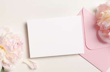 Wedding invitation card mockup with envelope and pink peony flowers, top view mockup with copy spaceの写真素材