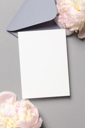 Blank invitation card mockup with envelope and pink peony flowers, top view mockup with copy spaceの写真素材